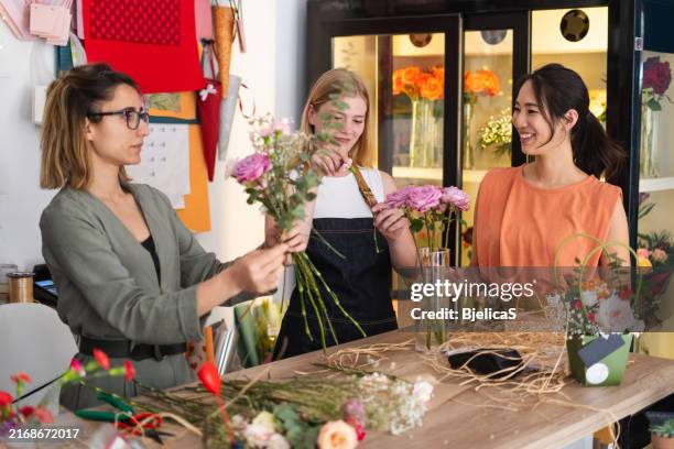 frauen, die an einem blumenarrangement-kurs im blumenladen teilnehmen - blumenschmuck stock-fotos und bilder