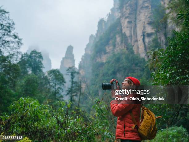 donna con macchina fotografica che esplora il parco forestale di zhangjiajie in cina - fotografo foto e immagini stock