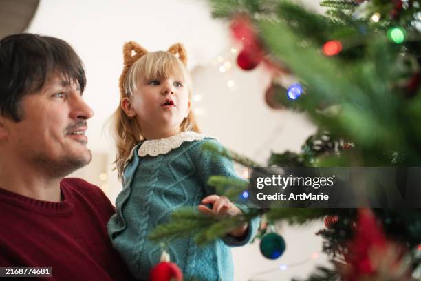family decorating christmas tree at home - decorating the christmas tree stock pictures, royalty-free photos & images