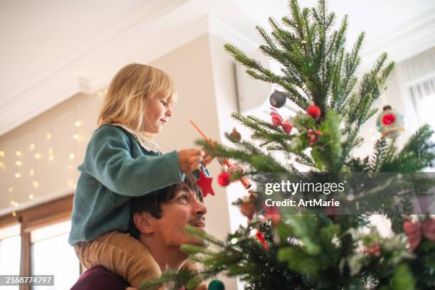 family decorating christmas tree at home - christmas ball on tree stock pictures, royalty-free photos & images