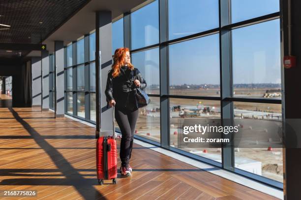 woman traveling by plane, waiting at the gate with wheeled suitcase - baggage tug stock pictures, royalty-free photos & images