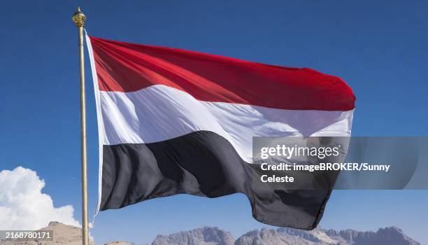 the flag of yemen, fluttering in the wind, isolated, against the blue sky - yemen stock pictures, royalty-free photos & images