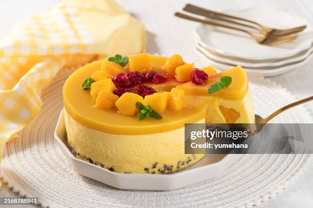 delicious no bake mango cheesecake with fresh diced mango pulp and raspberry topping on white wooden table. - mango slice on white stock pictures, royalty-free photos & images
