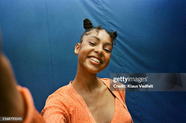 portrait of happy teenage girl taking selfie against blue backdrop - selfie stock pictures, royalty-free photos & images