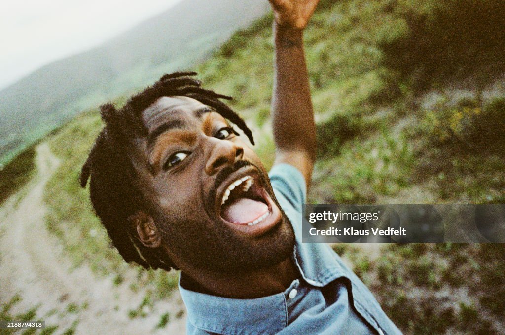 Portrait of young man screaming in field at safari resort