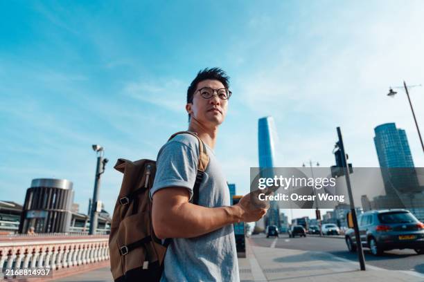 young asian man using smartphone on city street - location tracking stock pictures, royalty-free photos & images