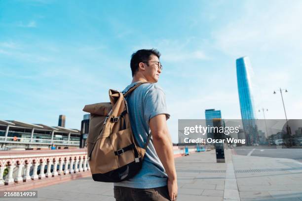 young asian man with backpack walking in modern city - rucksack stock pictures, royalty-free photos & images