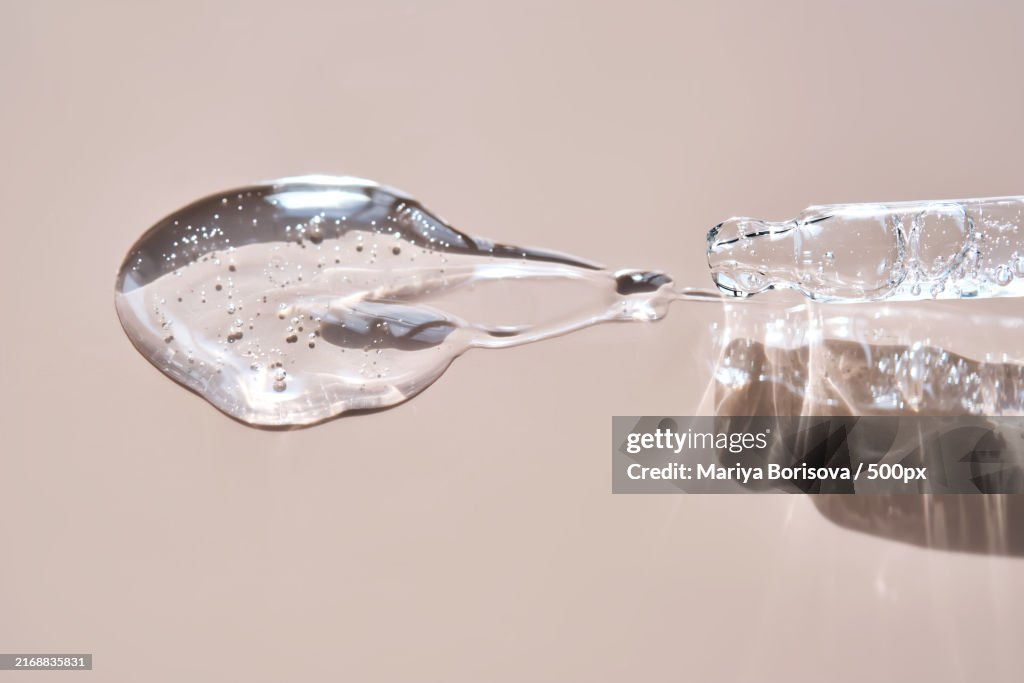 Pipette with cosmetic hyaluronic anti-aging serum on a dusty pink background