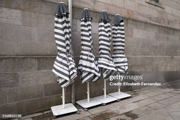 folded striped umbrellas by the wall - gartenschirm stock-fotos und bilder