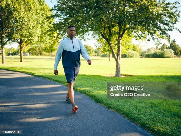 hombre maduro haciendo ejercicio en un parque por la mañana - paseo fotografías e imágenes de stock
