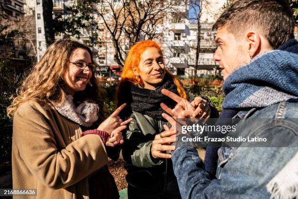 deaf friends communicating in sign language outdoors - group of people using sign language stock pictures, royalty-free photos & images