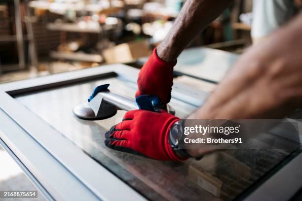 primer plano de un hombre mayor levantando vidrio usando ventosas en un taller de fábrica de vidrio - pvc fotografías e imágenes de stock