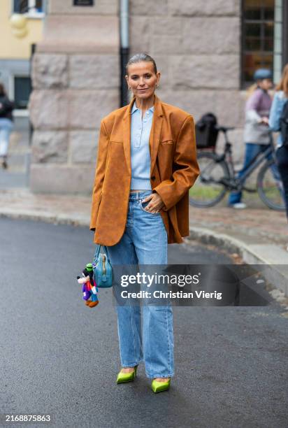 Janka Polliani wears brown oversized wild leather blazer, denim jeans, blue Miu Miu bag, polo shirt at Oslo Fashion Week 2024 on August 27, 2024 in...