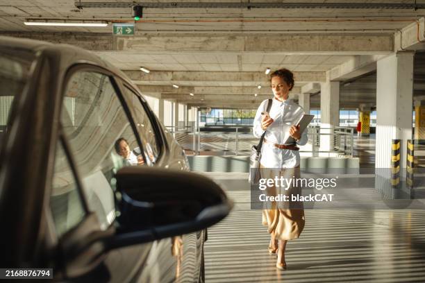 la bella donna adulta media si avvicina alla sua auto nel parcheggio - autista mestiere foto e immagini stock