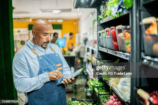 senior man working using digital tablet at store - retail clerk stock pictures, royalty-free photos & images