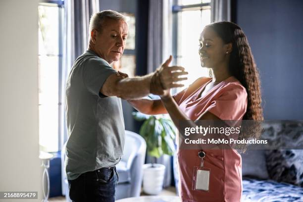 in home healthcare provider helping senior man with physical therapy in his home - disability insurance stock pictures, royalty-free photos & images
