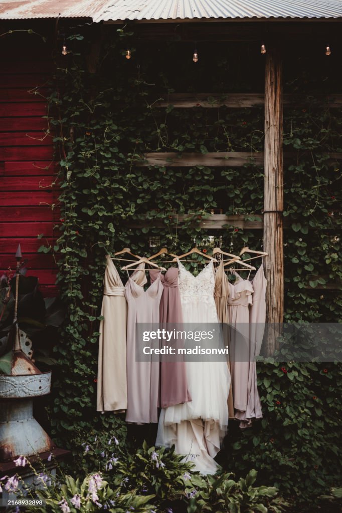 Bride's wedding dress hanging up with bridesmaid dresses