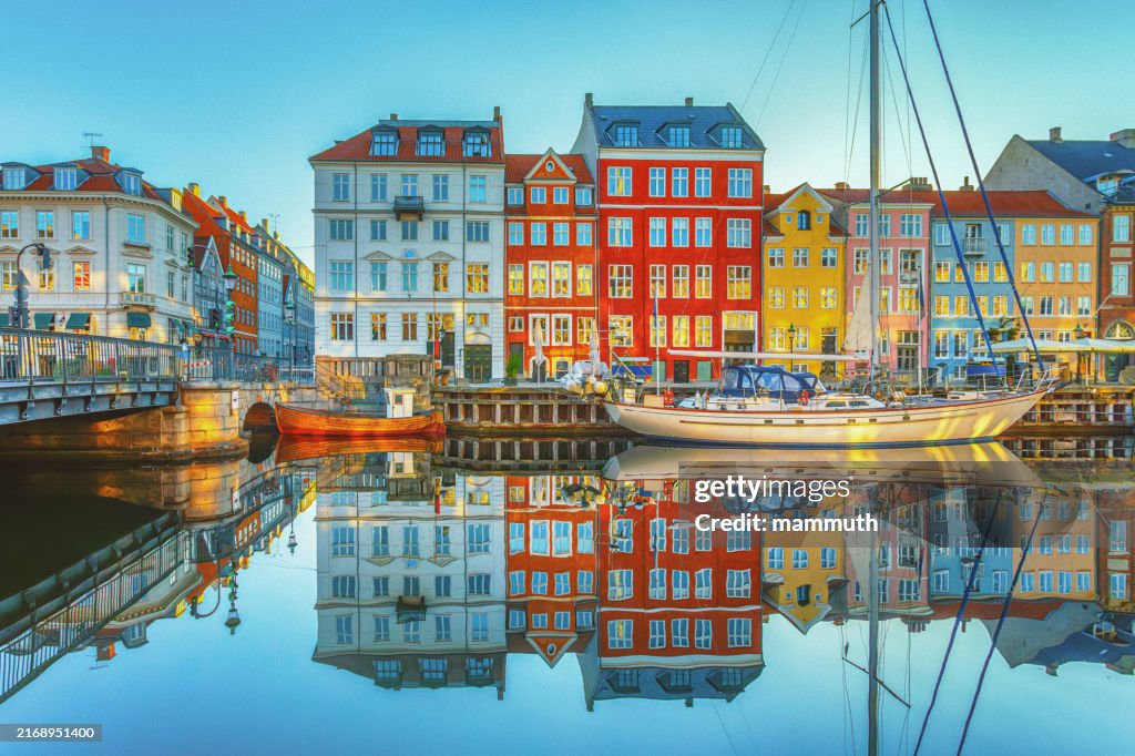 Nyhavn, Copenhagen, Denmark at Sunrise: A Tranquil Morning Scene with Historic Colorful Buildings Reflecting in the Calm Waters of the Canal