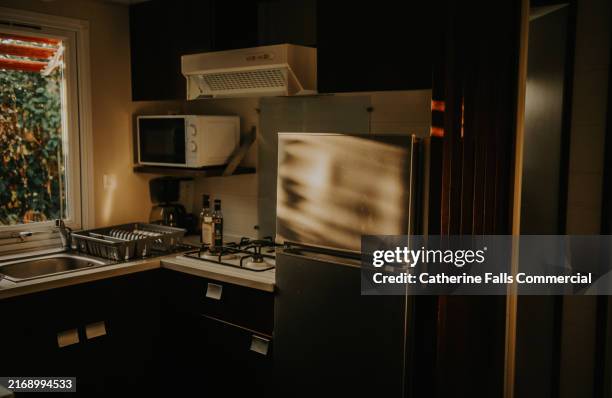a small kitchen within a mobile home, evening light illuminates the clean, compact space. - clean microwave stock pictures, royalty-free photos & images