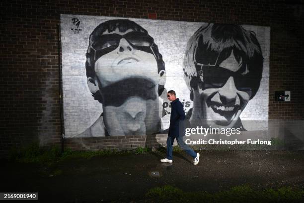 An Oasis fan is photographed next to a new mural depicting Liam and Noel Gallagher of Oasis, created by Manchester street artist Pic.One.Art., on the...