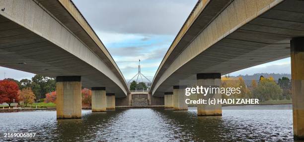 a view of the australian parliament building from underneath the commonwealth avenue bridge - lake burley griffin stock pictures, royalty-free photos & images