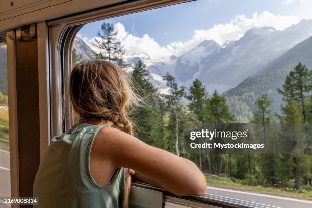 frau, die die alpenlandschaft vom zugfenster aus bewundert - europe travel stock-fotos und bilder