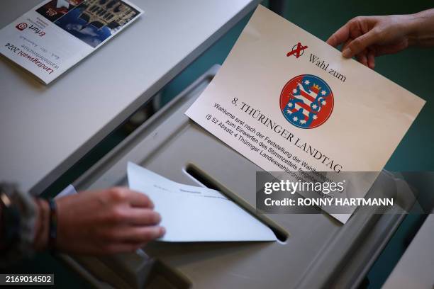 Woman casts her ballot paper for Thuringia's regional elections at a polling station in Erfurt, eastern Germany, on September 1, 2024. Looks down at...
