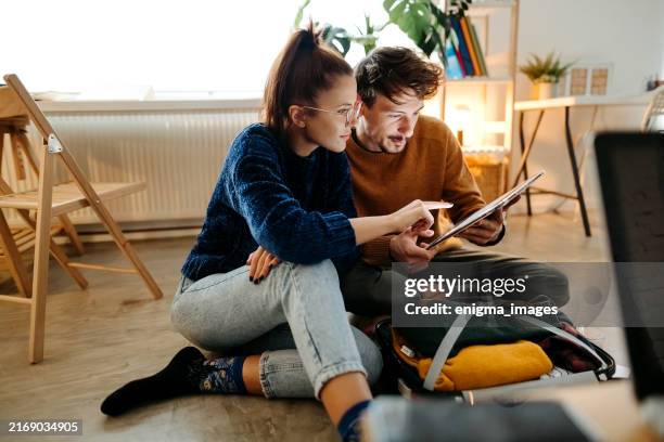 pareja planeando viaje de vacaciones y buscando información en tablet - hacer una reserva fotografías e imágenes de stock