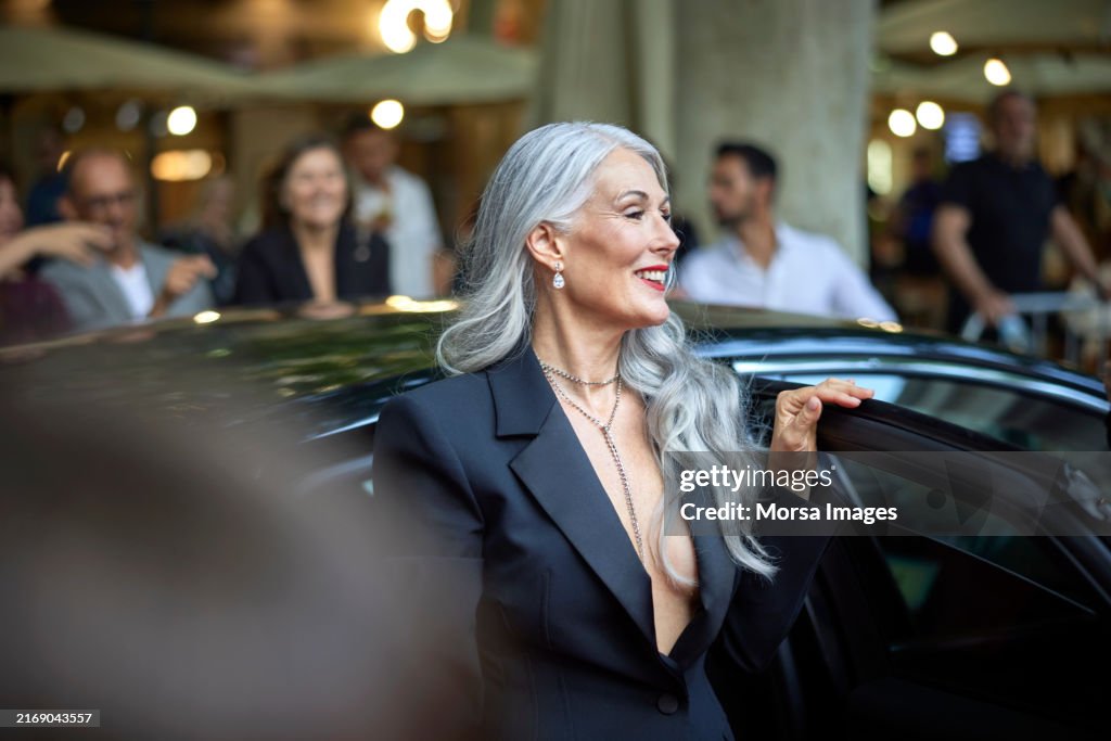 Smiling woman stepping out from car at event
