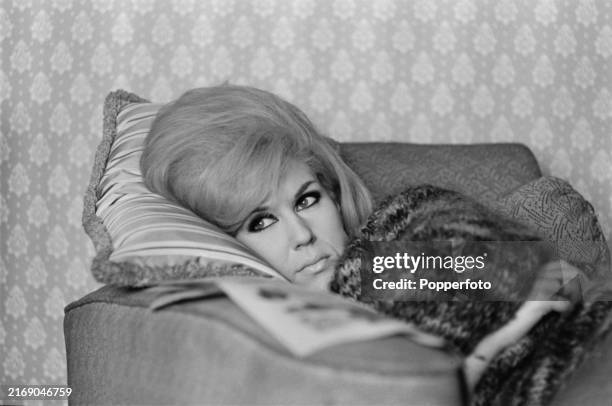 English singer Dusty Springfield lying on an armchair in the living room of her parents, Catherine and Gerard O'Brien, house on Wilbury Road in the...