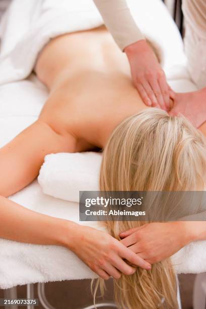 woman lying on stomach on a massage table receiving a massage - hand facing down stock pictures, royalty-free photos & images