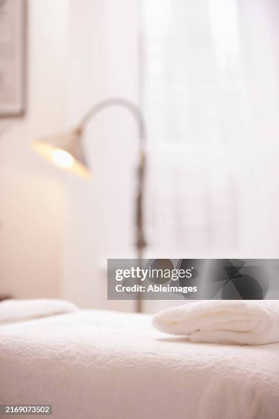 close up of a folded white towel on a massage table - spa treatment stock pictures, royalty-free photos & images