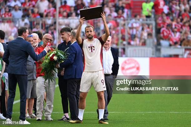 Bayern Munich's English forward Harry Kane raises the Top Scorer trophy, for finishing the season with the most goals scored in the German Bundesliga...