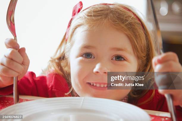smiling girl at dining table holding knife and fork - table manners stock pictures, royalty-free photos & images