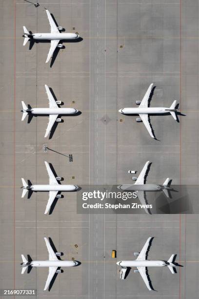 view from above airplanes parked on sunny airport tarmac - straßenmarkierung stock-fotos und bilder
