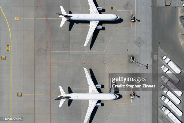 view from above airplanes parked on sunny airport tarmac - straßenmarkierung stock-fotos und bilder