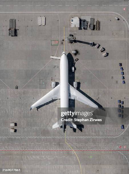 view from above airplane and service vehicles parked on sunny airport tarmac - airport tarmac stock pictures, royalty-free photos & images