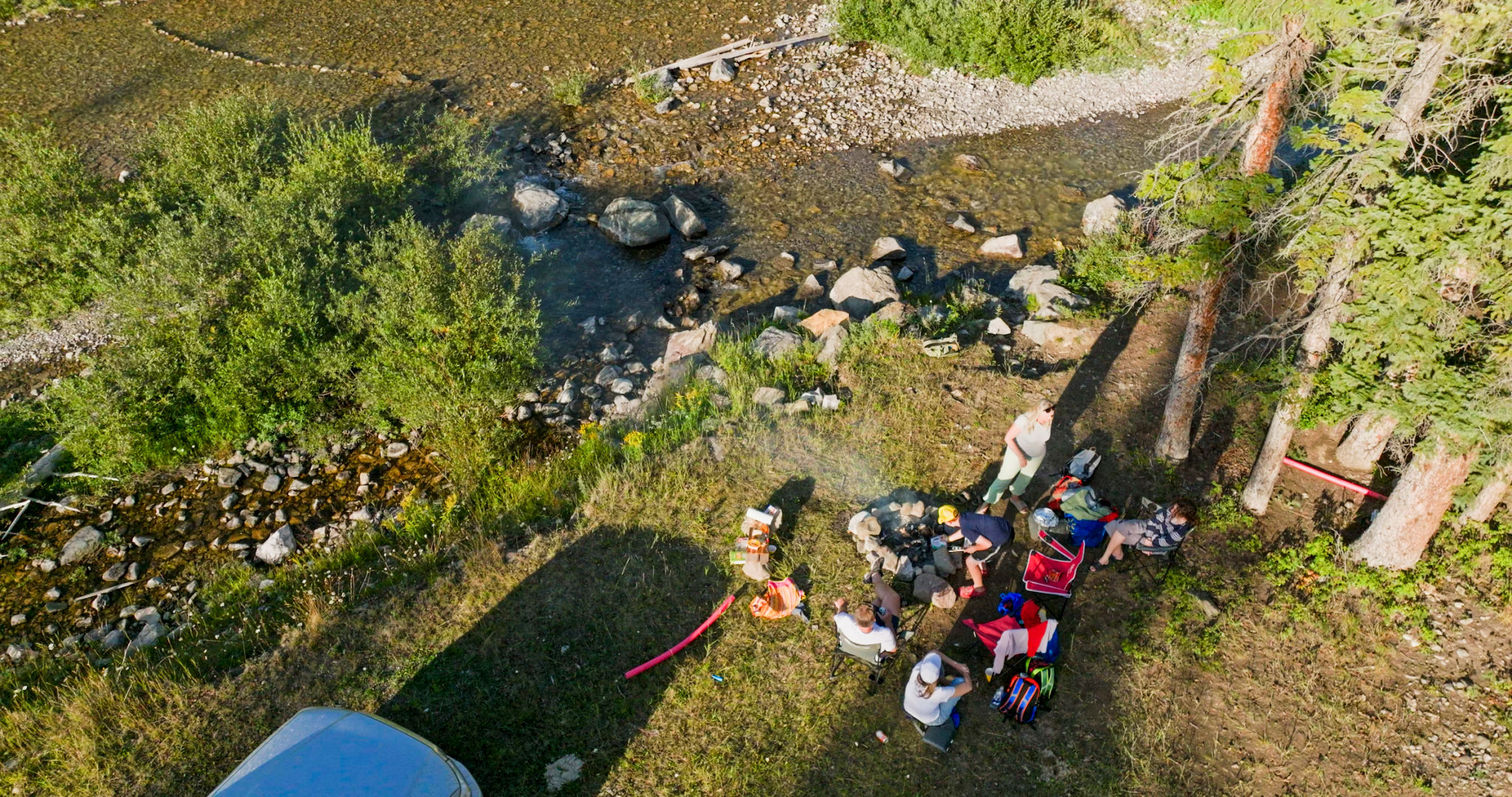 Aerial view of family enjoying mountain picnic beside stream Aerial view of family enjoying mountain picnic beside stream