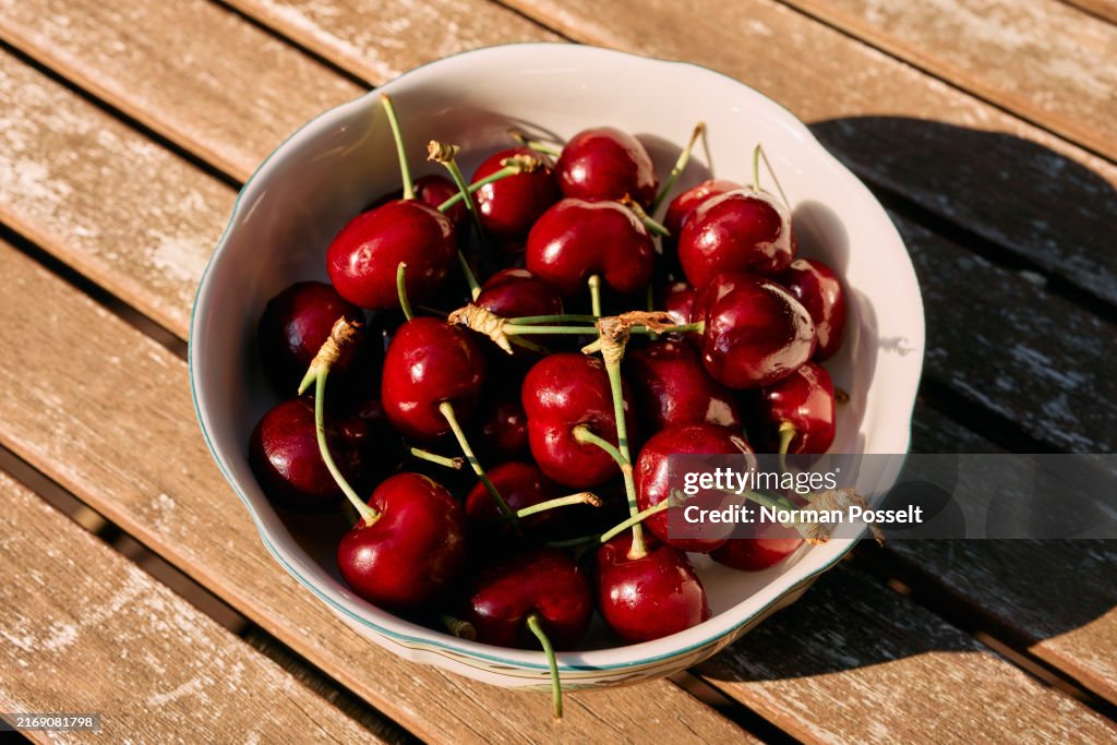 Still life close up vibrant red cherries in bowl on sunny table