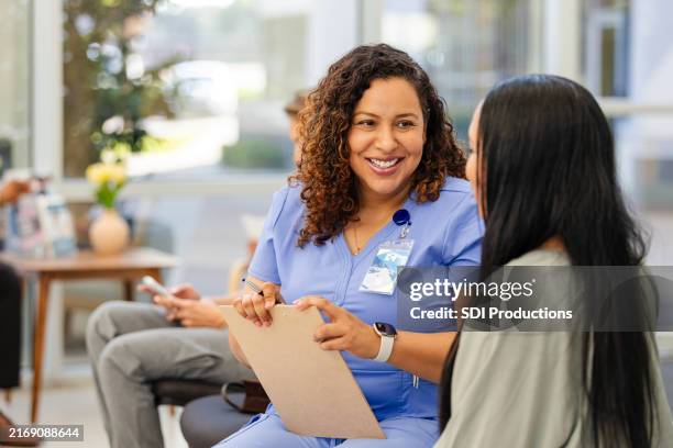 nell'atrio della clinica, donna irriconoscibile e infermiera parlano insieme - infermiere foto e immagini stock
