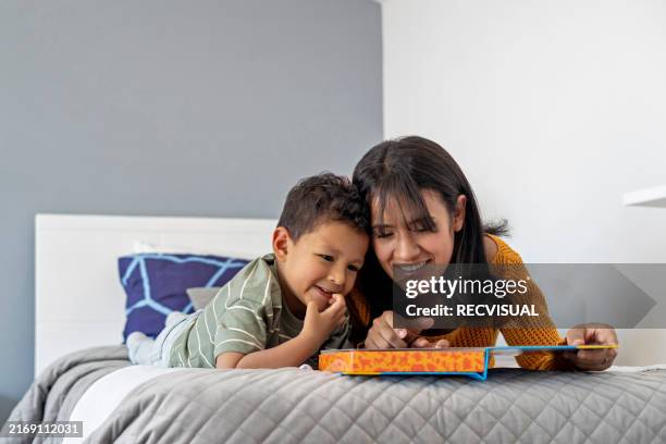 mother and son reading a book in the bedroom. - toddler stock pictures, royalty-free photos & images