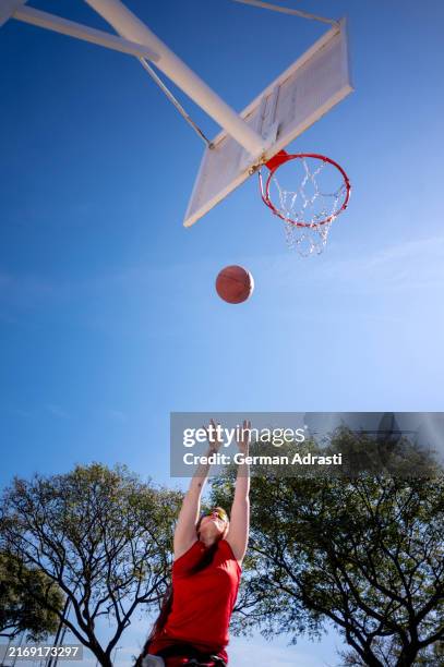 une jeune femme s’entraîne au basketball sur un terrain public - basket ball féminin photos et images de collection