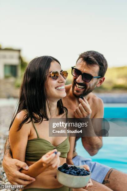 attractive couple having a snack by the pool - besparen stockfoto's en -beelden
