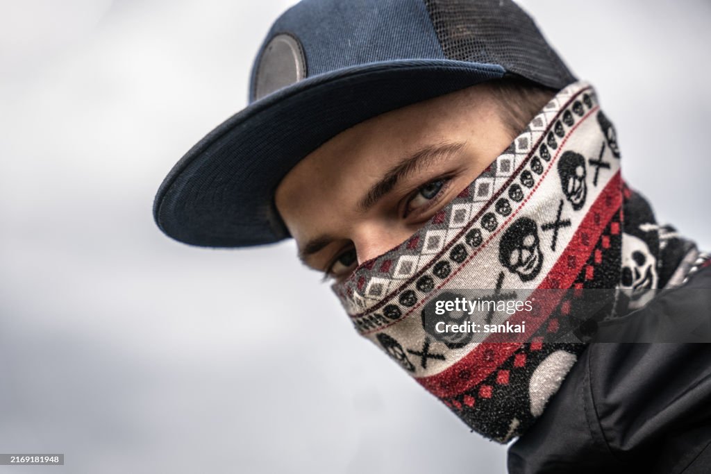 Portrait of the confident young man with bandana hiding his face, looking at camera