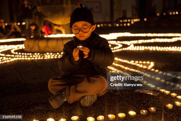 a little boy prayed for blessings during the temple lantern festival - religious celebration stock pictures, royalty-free photos & images