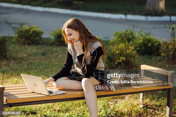 smiling young woman sitting on bench with laptop - sweater vest stock pictures, royalty-free photos & images