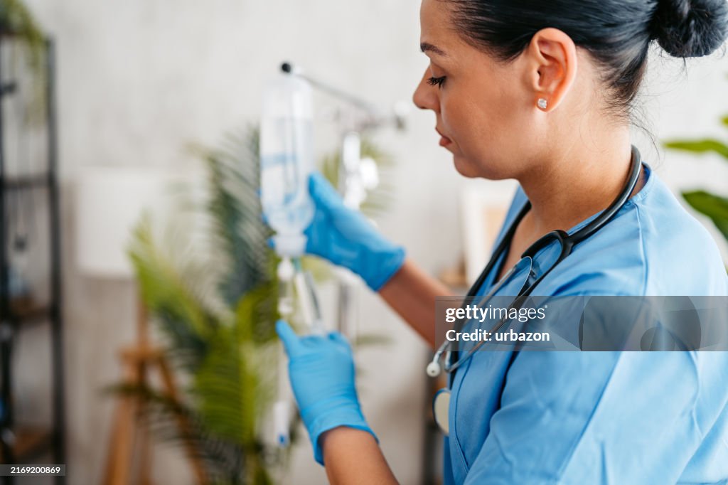 Home Care Nurse Preparing An IV Drip Indoors
