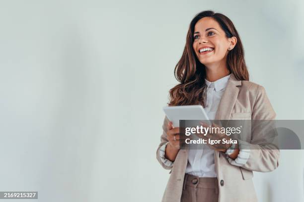 business woman holding a tablet in a modern office setting. - white blazer stock pictures, royalty-free photos & images