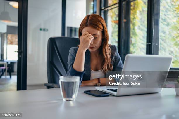 woman in office with laptop and water glass, feeling stressed out. - trött bildbanksfoton och bilder