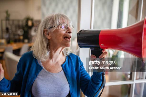 woman holding a red megaphone in a bright room - outspoken person stock pictures, royalty-free photos & images